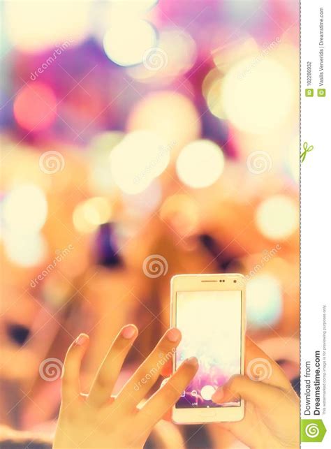 Hand holding smartphone at music festival